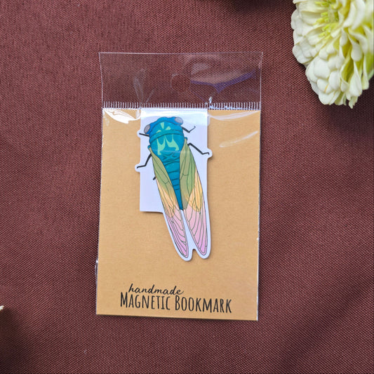 Handmade magnetic bookmark with a colorful insect design on a brown fabric background.